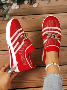 Close-up detail of red knit sneaker with gold chain and white striped pattern