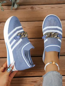 Close-up of women's blue fly-knit casual sneakers featuring chunky golden chain detail.
