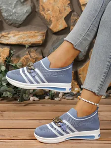 Detail of light blue fly-woven sneakers with gold metal chain and striped pattern