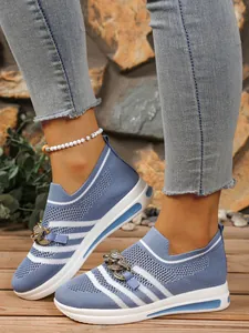 Macro view of blue flyknit sneakers with elegant metal chain detail and wedge sole.
