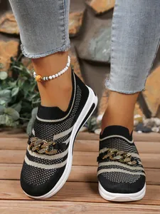 Detail shot of fly-knit hollow loafers with decorative metal chain and wedge sole.