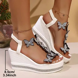 Detail view of white wedge sandals with butterfly motifs and rhinestone heels.