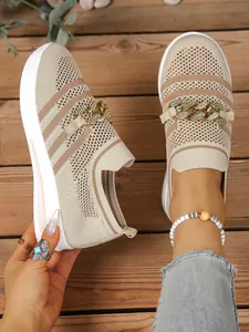 Close-up of beige knit shoes with gold chain detail and breathable hollow mesh.
