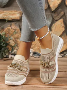 Close-up of breathable flyknit mesh sneakers featuring gold chain and wedge heel design