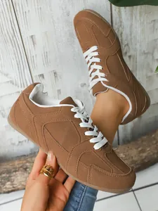 Primer plano de zapatillas retro de gamuza marrón con cordones blancos en fondo rústico