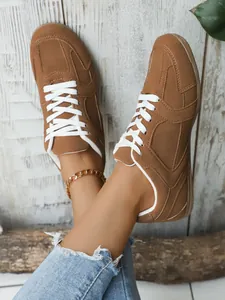 Vista detallada de zapatillas vintage marrones con cordones blancos y vaqueros azules