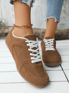 Vista detallada de zapatillas retro de ante marrón para mujer con cordones blancos