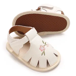Gros plan de sandales blanches pour bébé avec broderie florale et semelle à pois