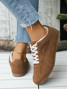 Primer plano de zapatillas retro de ante marrón con cordones blancos en suelo de madera