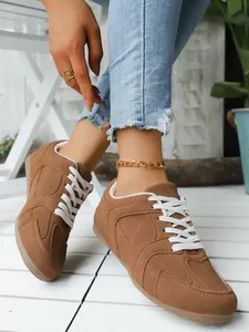 Vista detallada de zapatillas retro de gamuza marrón con cordones blancos en un modelo