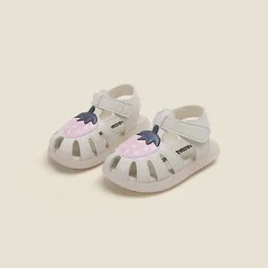 Détail des sandales blanches pour bébés filles avec un motif de fraise rose