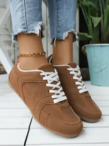 Primer plano de zapatillas retro de ante marrón con cordones blancos y tobillera dorada