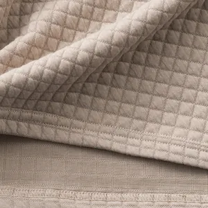 Close-up of heavyweight jacquard fabric with small square pattern on beige polo shirt