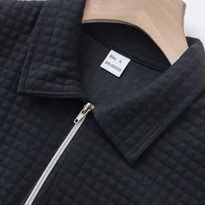 Detail of black polo shirt with quilted square texture and front zipper closure