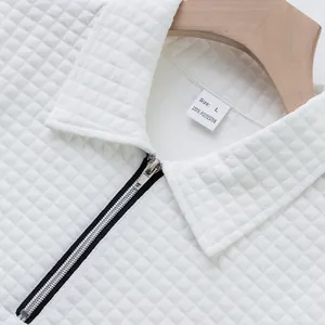 Close-up of white waffle knit polo shirt showing jacquard texture and zipper collar.