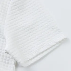 Macro view showing the detailed heavyweight jacquard small grid texture of white polo shirt