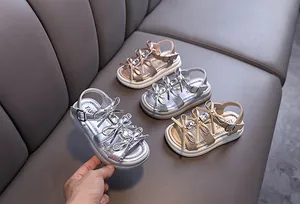 High-angle detail shot of silver and gold girls' rhinestone princess sandals with bows.