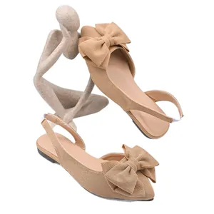 Élégantes ballerines slingback beiges à bout pointu avec grand nœud sur fond blanc.