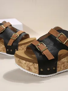 Close-up of buckled platform wedge sandals with cork texture and white jagged sole.