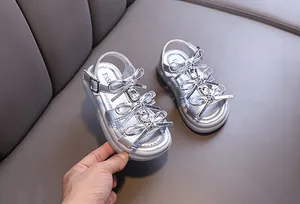 Detailed view of silver girls sandals decorated with bows and sparkling crystals
