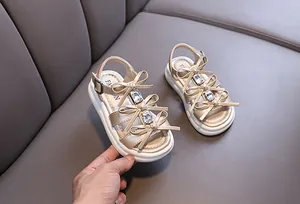 Close-up detail of girls' champagne gold princess sandals featuring elegant bows and rhinestones