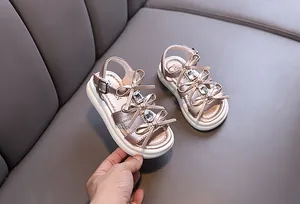 Detailed view of children's pink metallic sandals with crystal bows and thick soles.