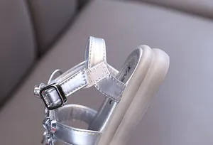 Detailed view of the silver metallic strap and adjustable buckle on girls sandals