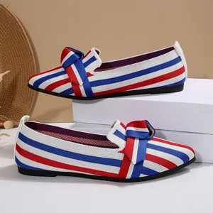 Dettaglio delle ballerine a punta in maglia a righe rosse e blu con fiocco decorativo