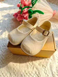 Elegante cremefarbene Mary Jane Prinzessinnenschuhe für Mädchen in einer süßen Kulisse.