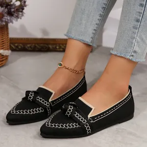 Dettaglio ravvicinato di scarpe piatte in rete traspirante con fiocco e motivo catena.
