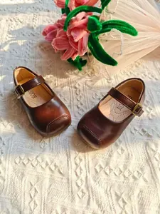 Nahaufnahme der klassischen braunen Mary Jane Lederschuhe für Kinder mit Blumendekor.