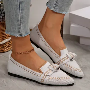Primo piano di ballerine bianche in flyknit a punta con fiocco e raffinati motivi oro