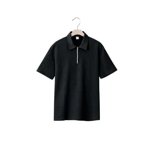 Detailed view of black textured jacquard fabric and zipper collar on men's polo shirt