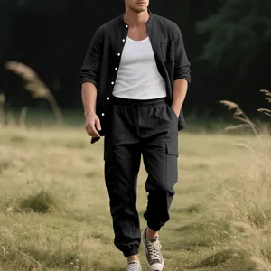Male model wearing black linen long-sleeve shirt and matching cargo pants in a field