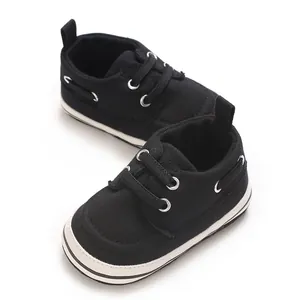 Detailed macro view of black canvas baby walking shoes with white laces and soles