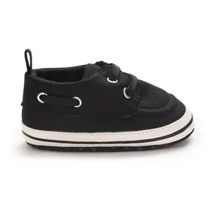 Detailed side view of a black canvas infant walking shoe with laces and a white rubber sole
