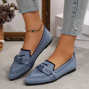 Primo piano di ballerine blu in maglia intrecciata con punta affusolata e fiocco
