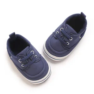 Macro view of navy blue canvas baby walking shoes featuring white rubber soles and laces
