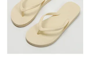 Detailed macro view of cream-colored flip-flops highlighting the sole texture and finish