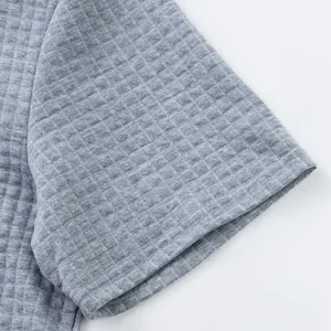 Detailed macro view of the grey textured jacquard fabric on a men's polo shirt sleeve.