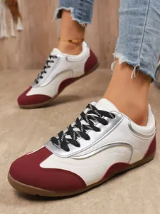 Close-up of women's color-block casual sneakers with burgundy and silver accents.