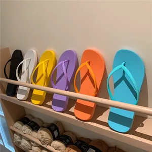 Vibrant colorful summer flip-flops in yellow blue purple and orange on a wooden shelf