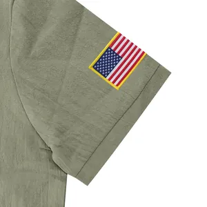 Detail van het Amerikaanse vlagborduursel op de mouw van een groene linnen poloshirt