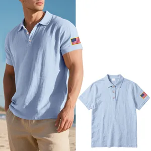 Detail van een lichtblauw linnen poloshirt met de Amerikaanse vlag geborduurd op de mouw
