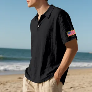 Detailweergave van een zwarte linnen polo voor heren met een Amerikaanse vlag op het strand