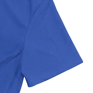 Détail macro du t-shirt bleu à maille gaufrée montrant la texture de tissu respirante