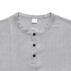 Detailed view of grey textured Henley shirt neckline with buttons and size tag.