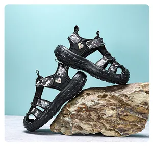 Profile view of boy's closed-toe sandals with camouflage detail on outdoor rock background
