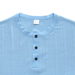Close-up view of a light blue slub texture Henley shirt with buttons and size tag.