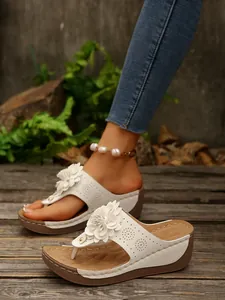 Detailed view of elegant white wedge flip-flops for women with stylish flower décor